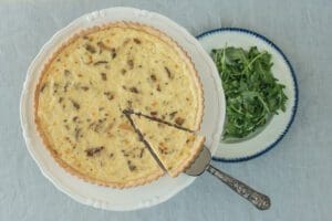 Sliced quiche beside fresh arugula