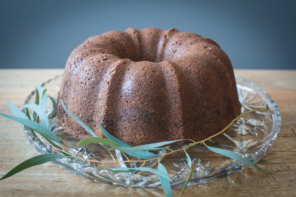 Bundt cake on glass plate with greenery