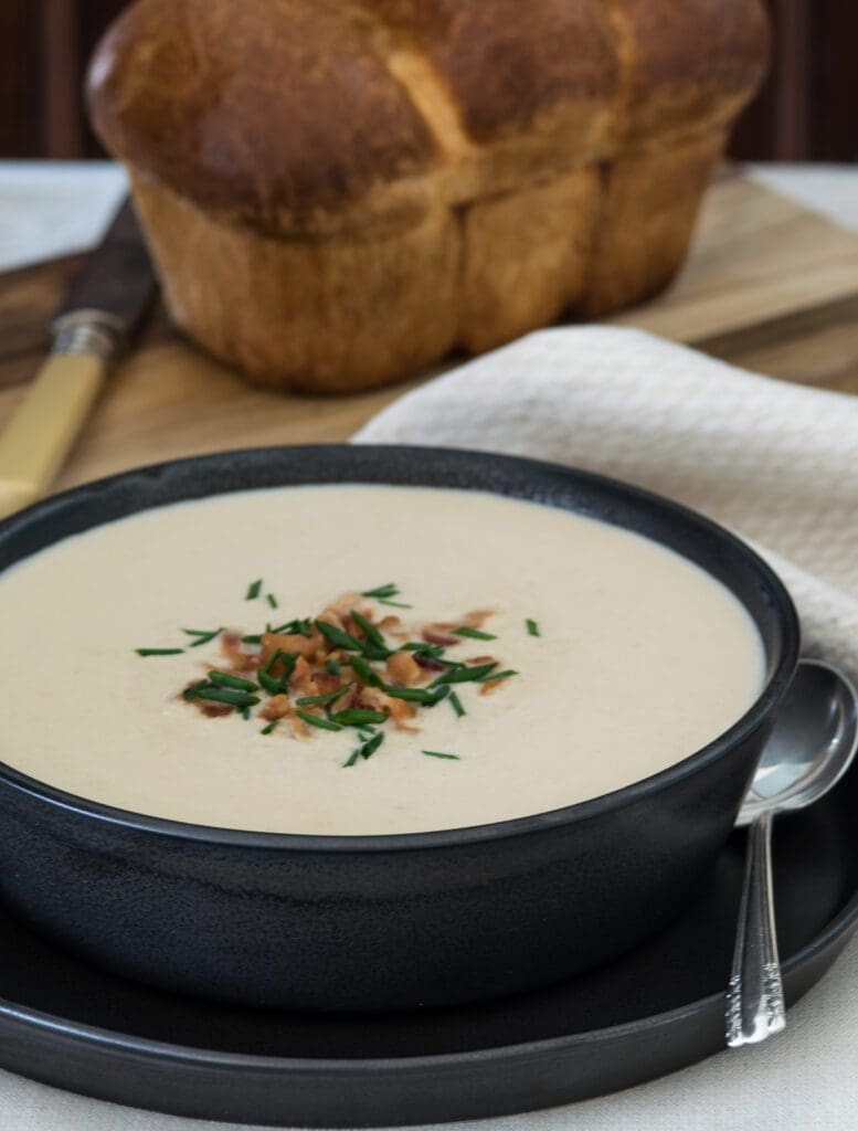 Black bowl of cauliflower soup with chives