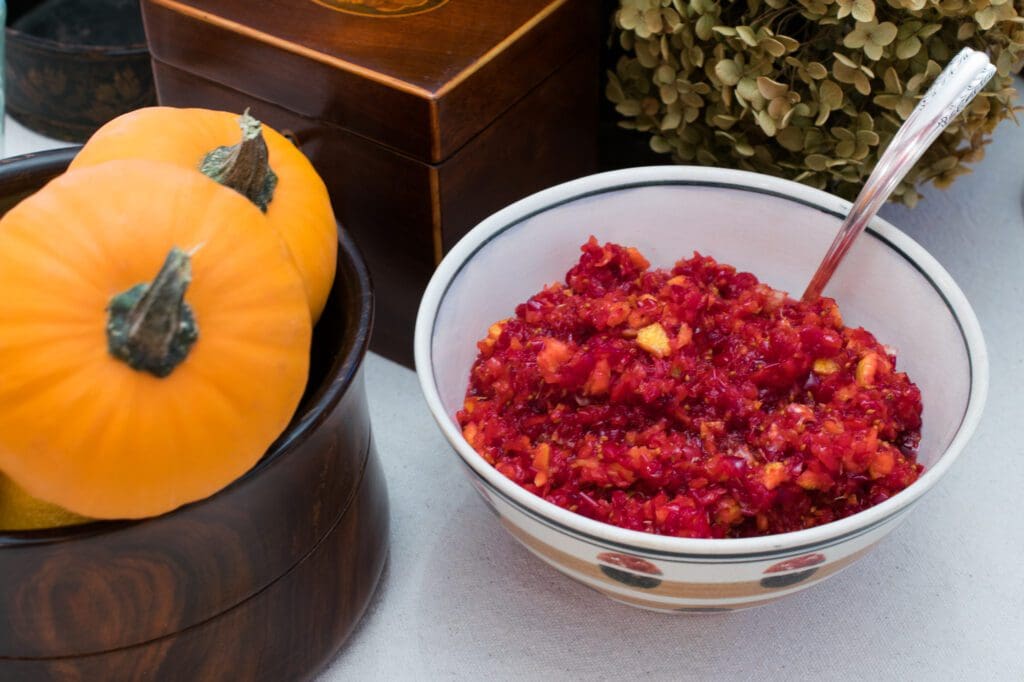 Bowl of cranberry relish next to pumpkins