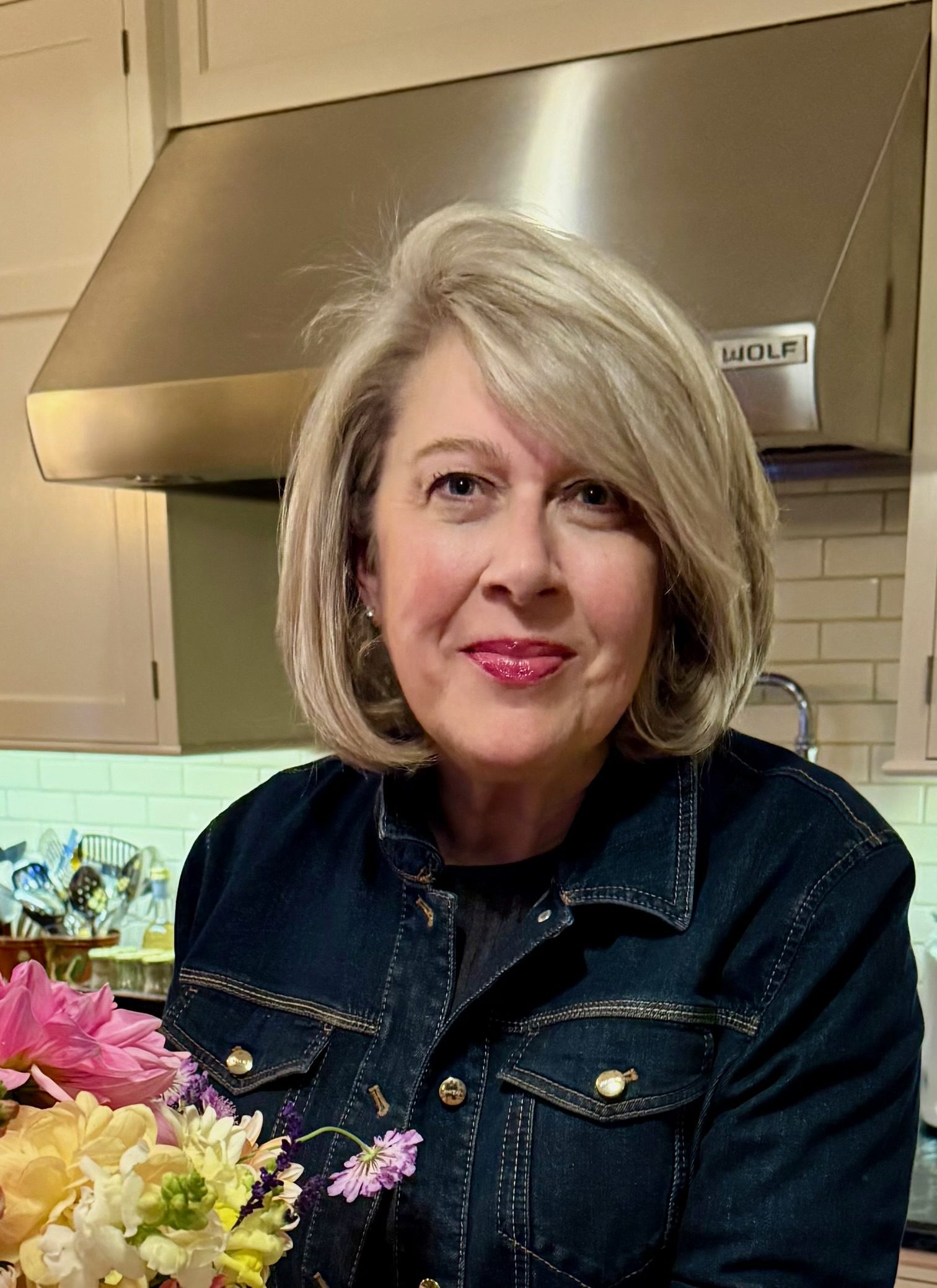 Woman holding flowers in a kitchen.