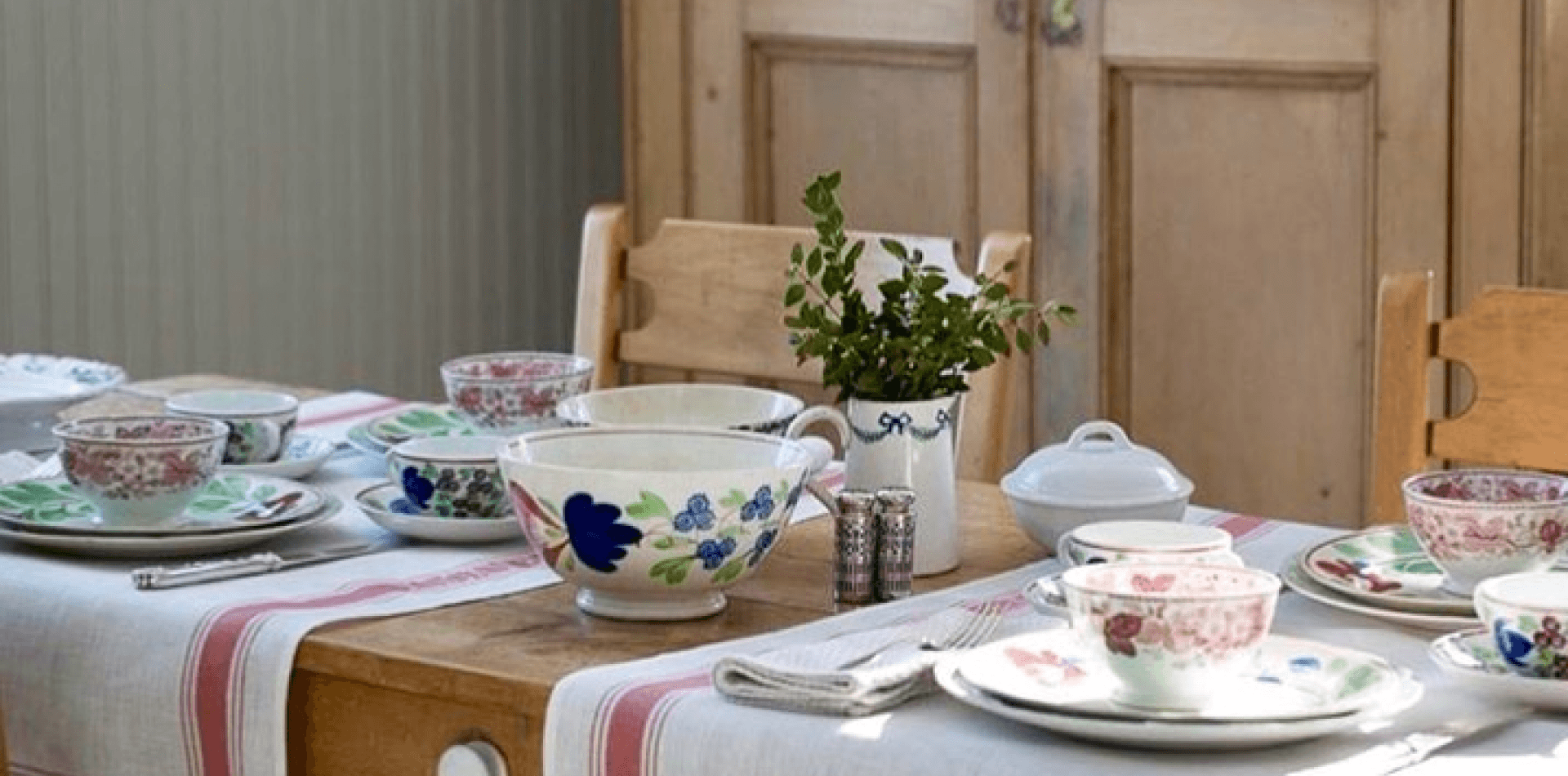 Table set with colorful crockery and plants.