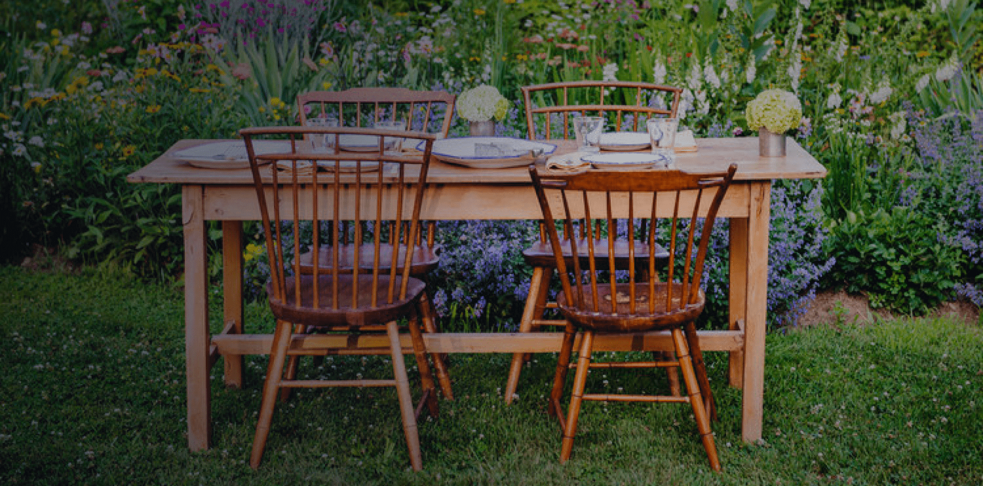 Outdoor wooden table with chairs in garden.