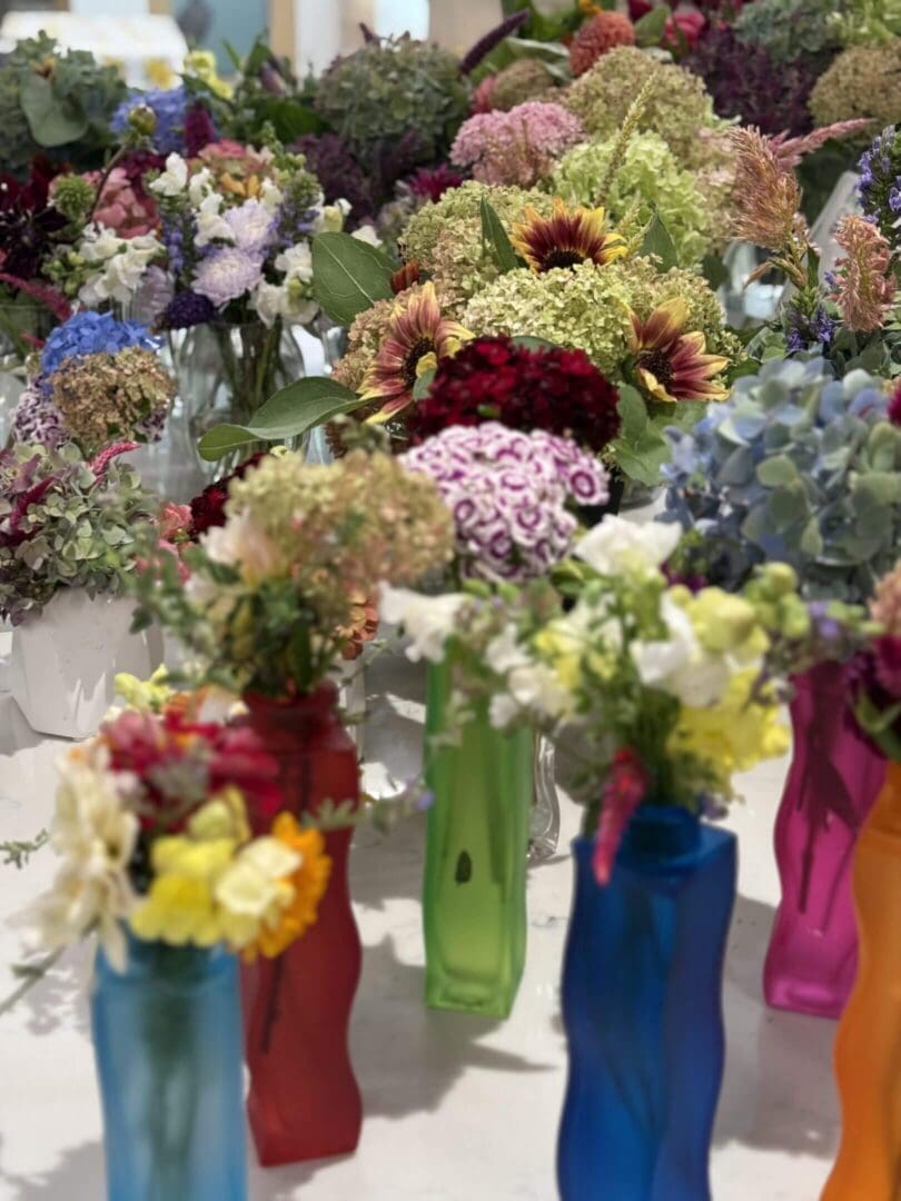 Colorful flowers in vibrant, assorted vases.