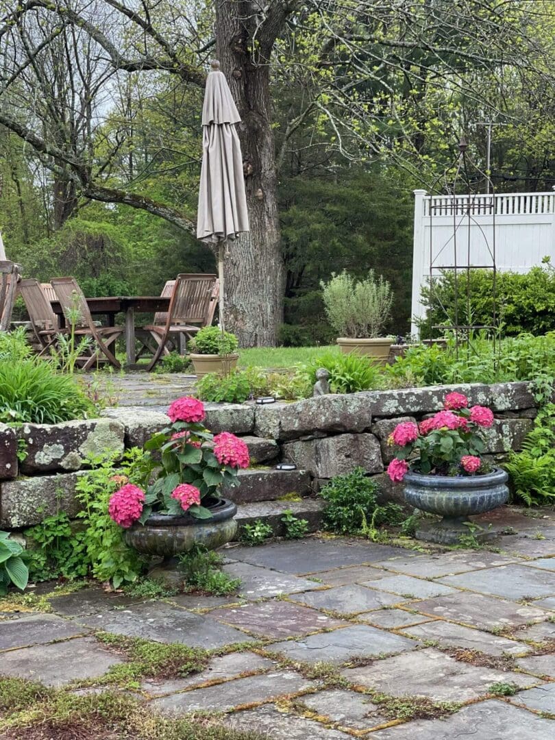 Garden patio with pink flowers and furniture.