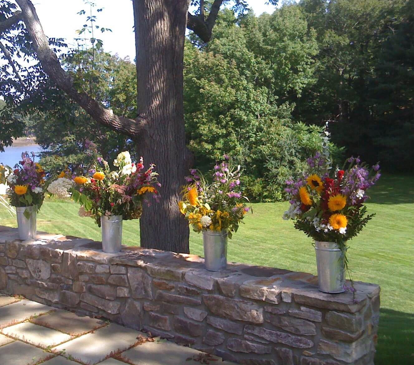 Vibrant flowers in metal vases on wall.