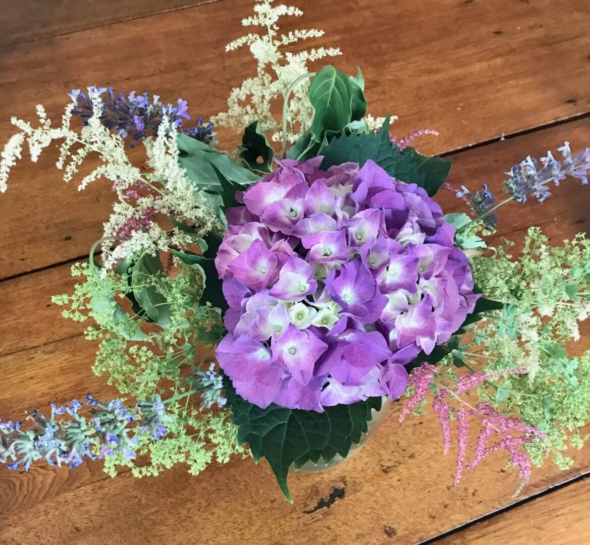 Purple hydrangea bouquet on wooden table.