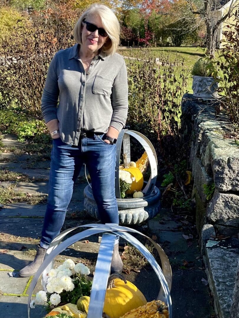 Woman in sunglasses by pumpkins and flowers